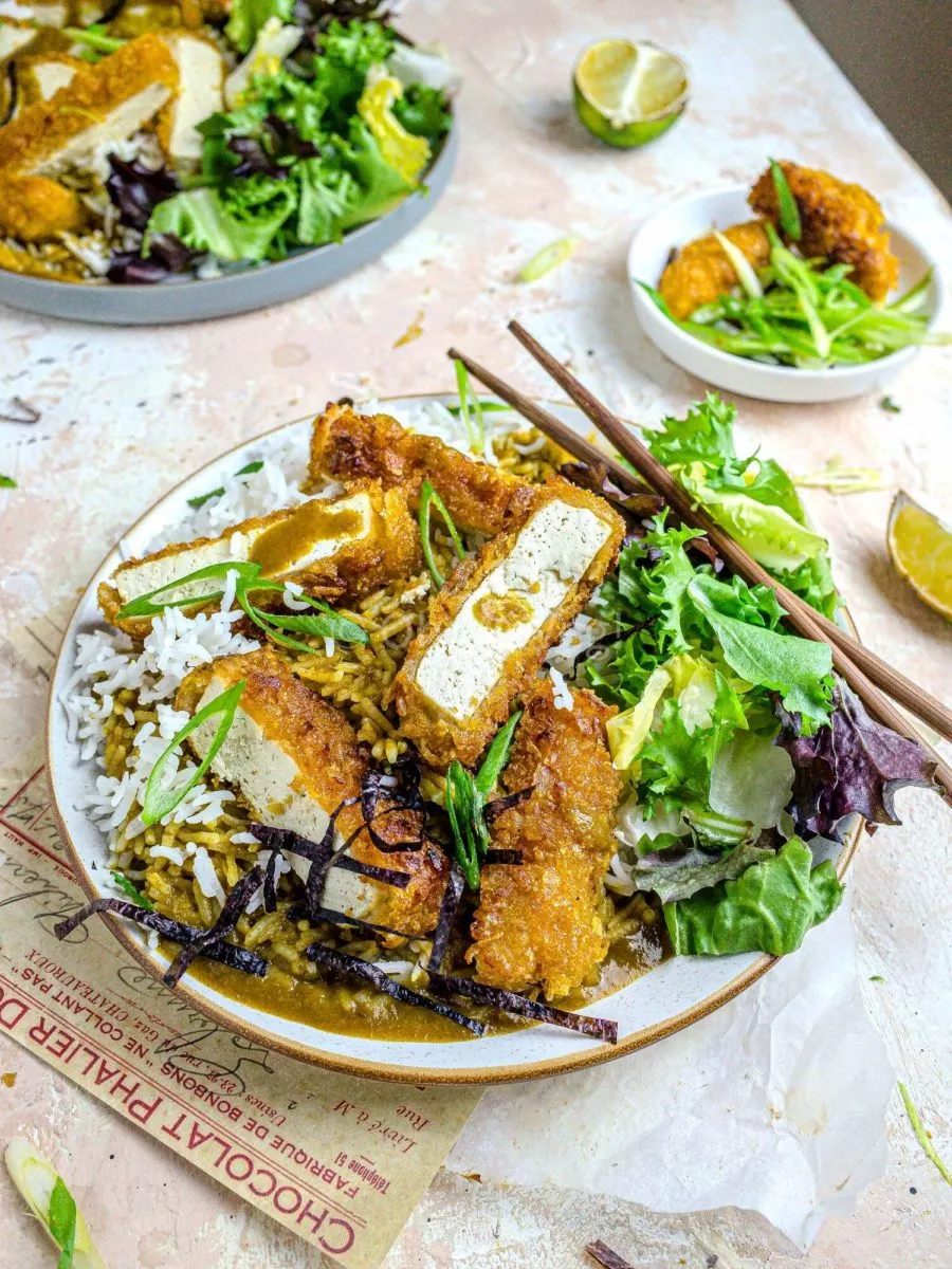 Vegan katsu curry with tofu and salad on a white plate.