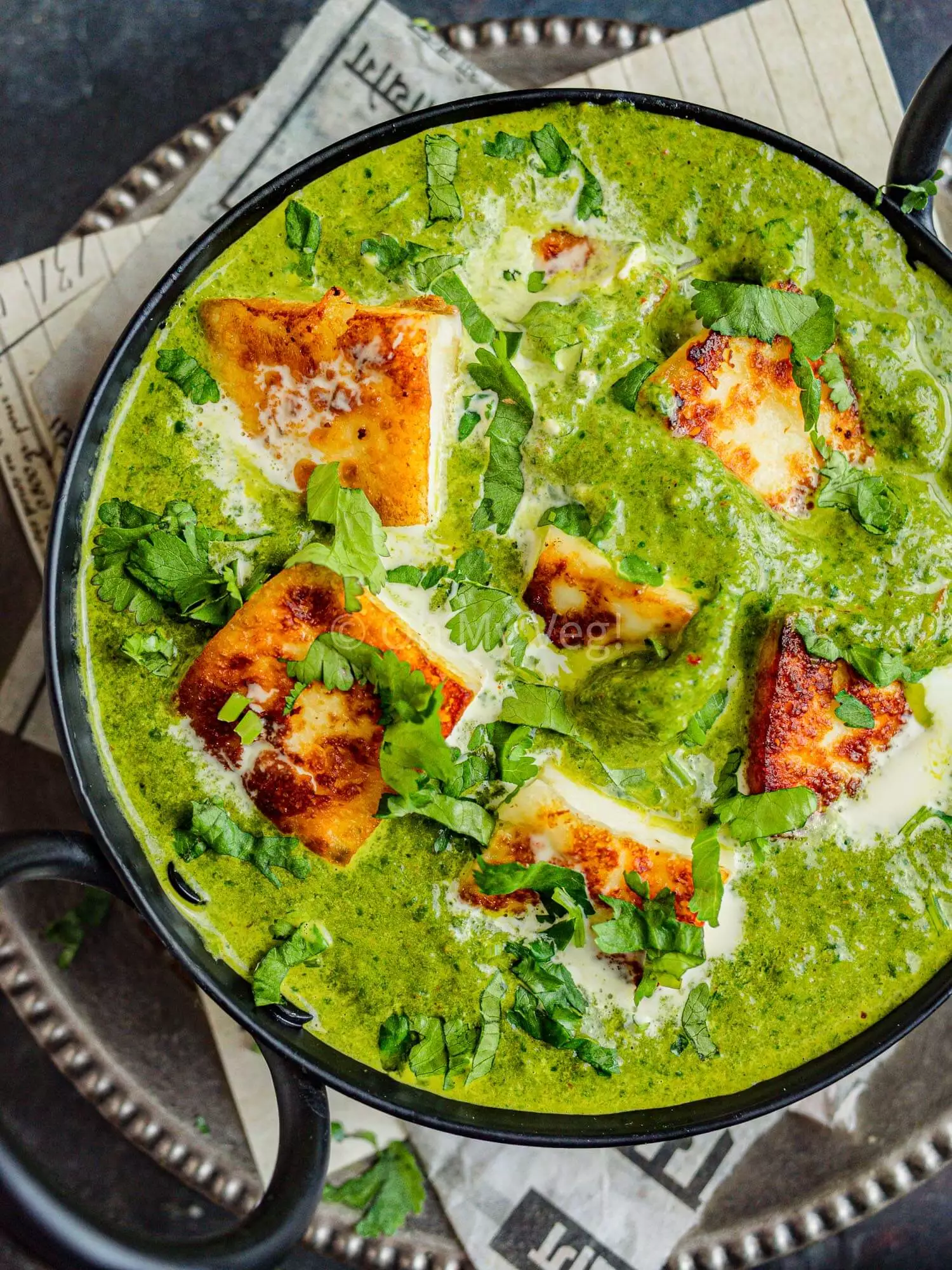 Palak paneer spinach curry in a black kadai. 