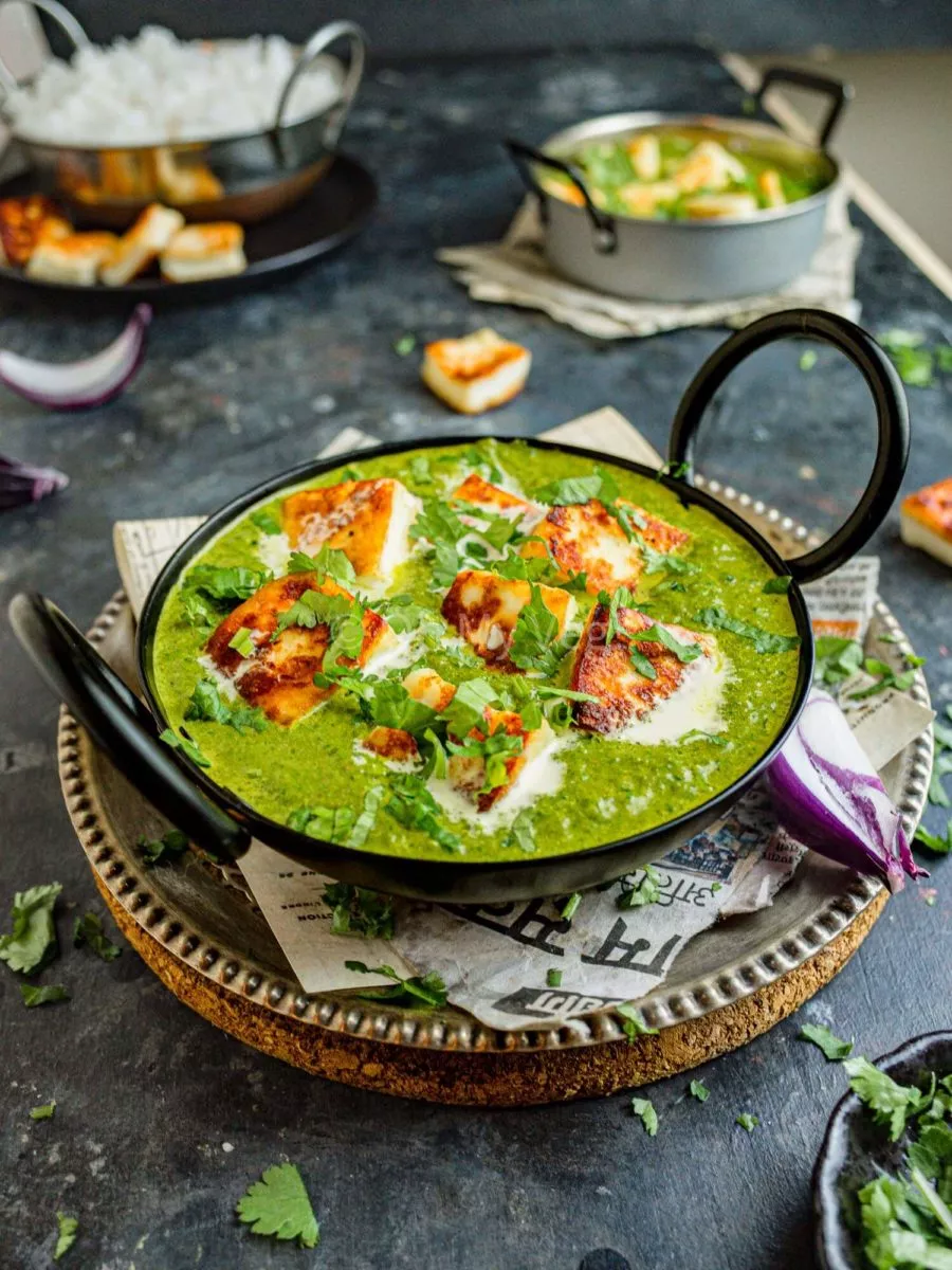 Spinach curry with Indian cheese, palak paneer in a black bowl. 