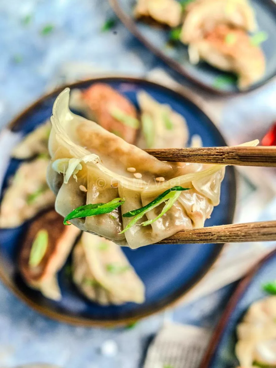 Chopsticks holding a vegetable gyoza.