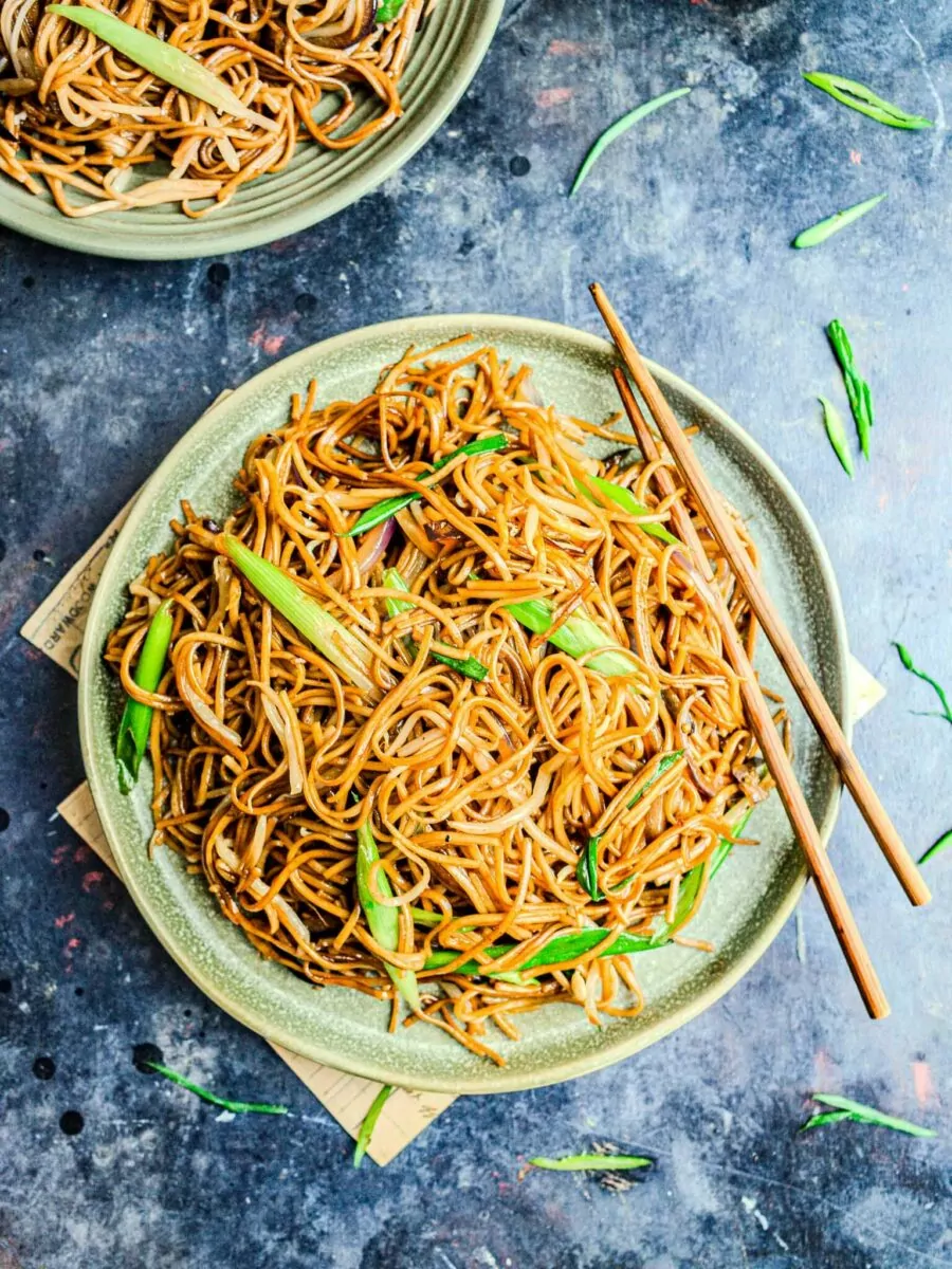Soft noodles with beansprouts on a green plate with chopsticks.