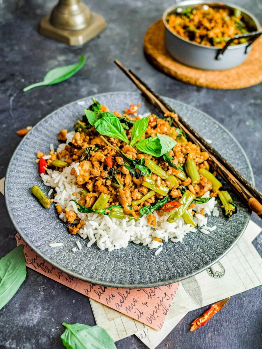 Tofu pad krapow with rice on a grey plate with chopsticks.