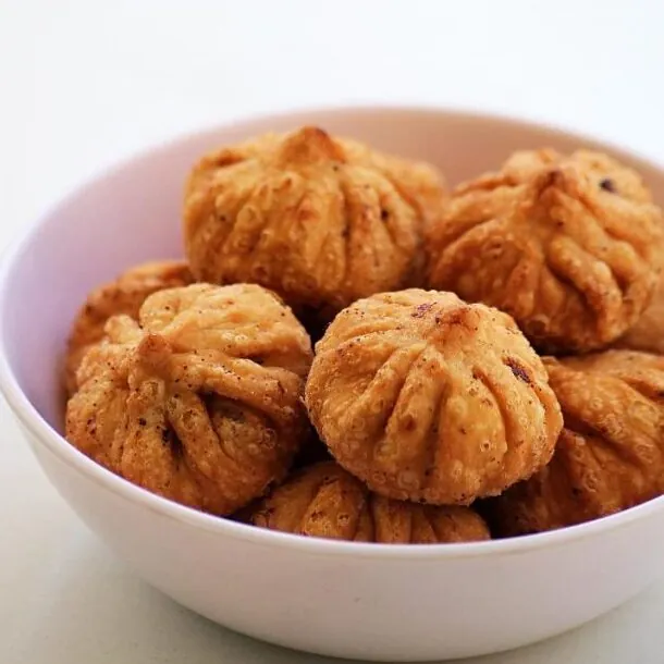 Fried modak in a white bowl.