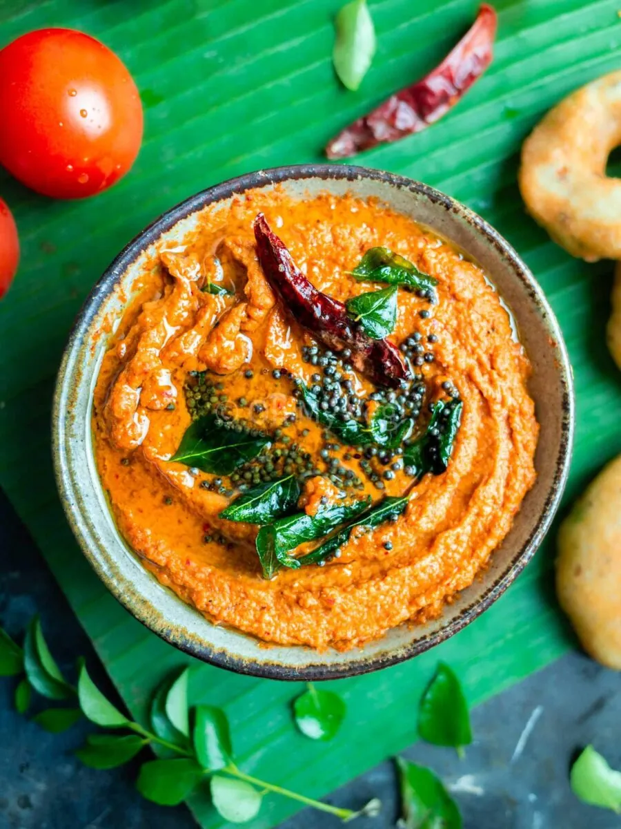 Kara chutney in a bowl, with medu vada on the side.