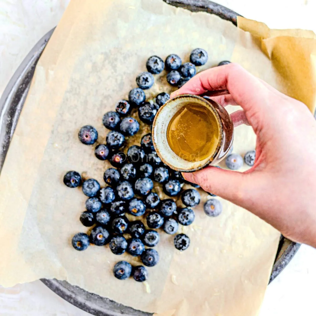 Pouring honey over blueberries.