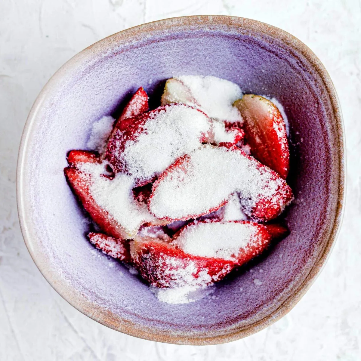 Strawberries covered with sugar in a bowl.
