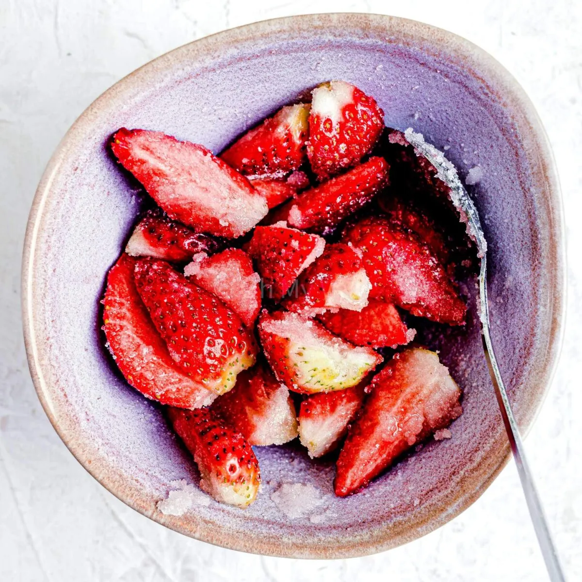 Strawberries mixed with sugar and lemon in a bowl.