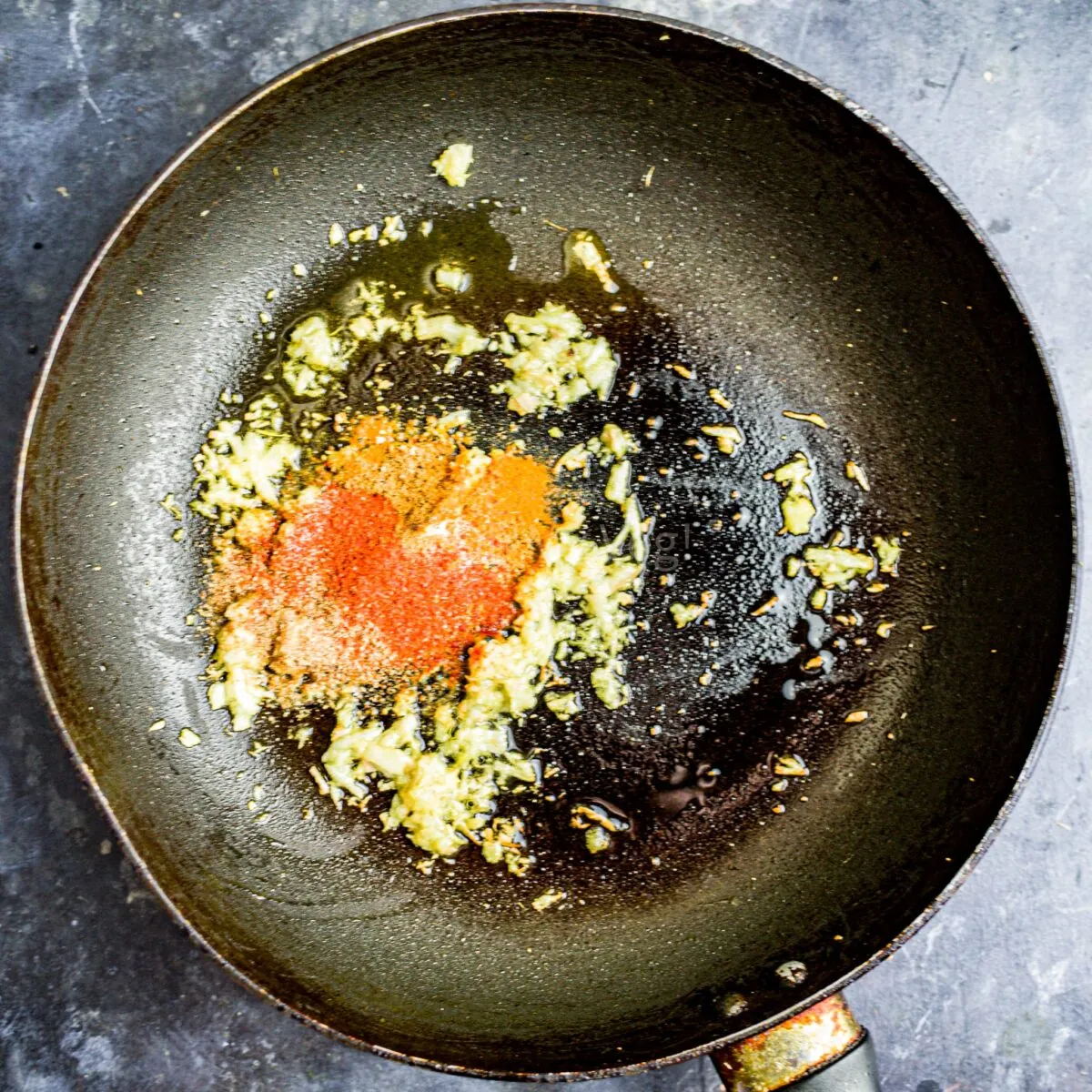 Ginger garlic paste and spices in a black frying pan.