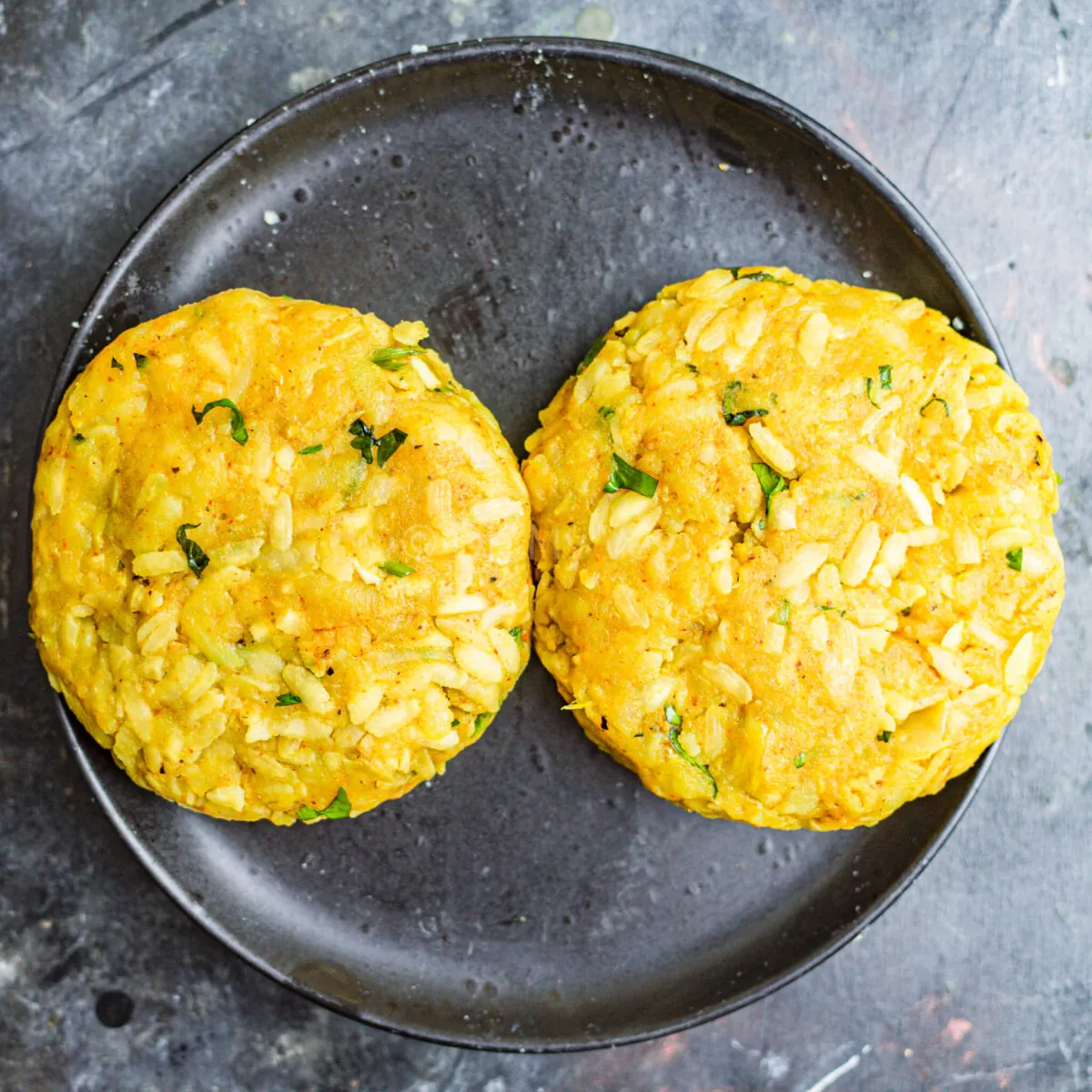 Two aloo tikki patties on a plate.