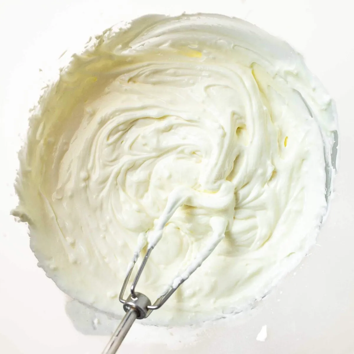 Whisked cream, sugar, and yoghurt in a bowl.