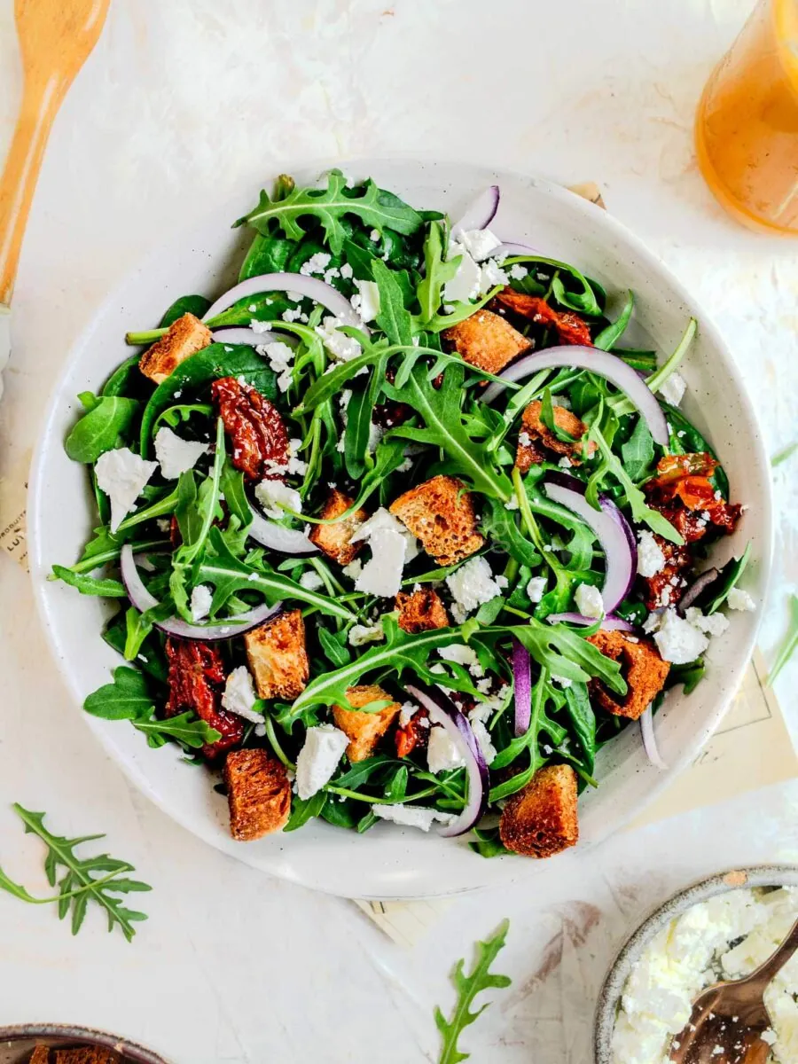 Spinach and arugula salad in a white bowl.