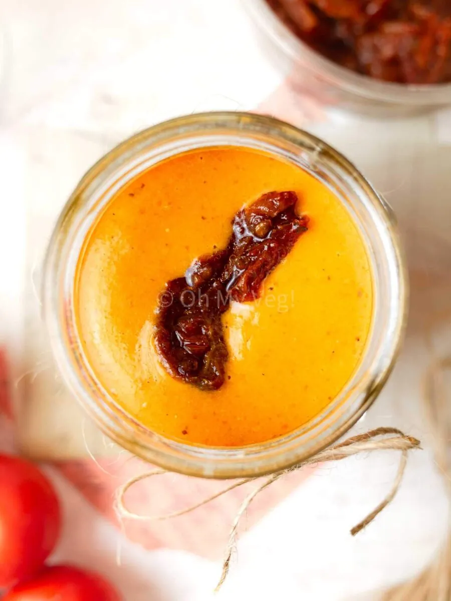 Sundried tomato dressing in a jar with a tomato on top.